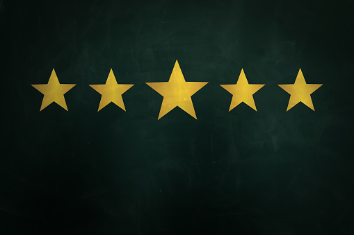Quality evaluation. Golden stars on green chalkboard
