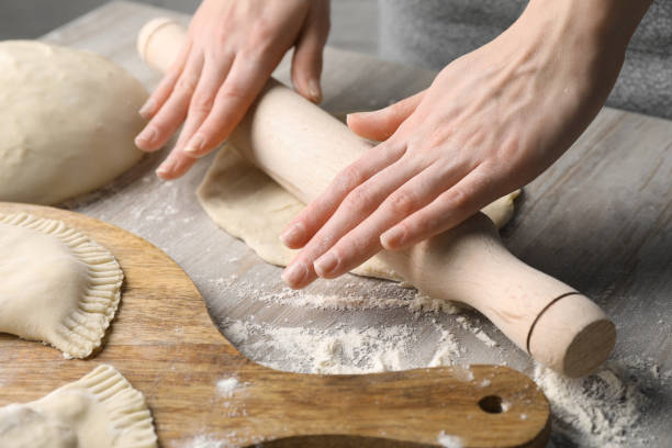 istock Woman rolling dough for chebureki at wooden table, closeup 1469901160
