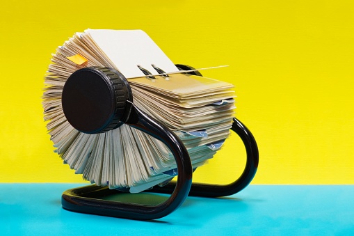 Rolodex file organizer sitting open on a colorful plain yellow and blue background with copy space.