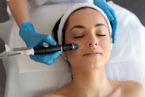 Close-up of woman getting facial hydro microdermabrasion peeling treatment. Female at cosmetic beauty spa clinic. Hydra vacuum cleaner. Cosmetology concept