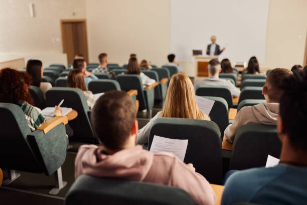 istock Rear view of large group of students on a class at lecture hall. 1469905151