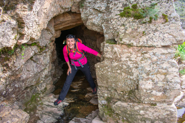 istock smiling woman hiker emerging from a cave in the mountain rocks 1469909172