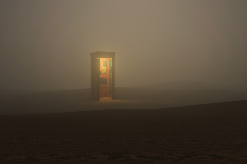 lighted telephone booth isolated in the foggy desert