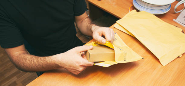 The man is packing the product into the yellow envelope stock photo