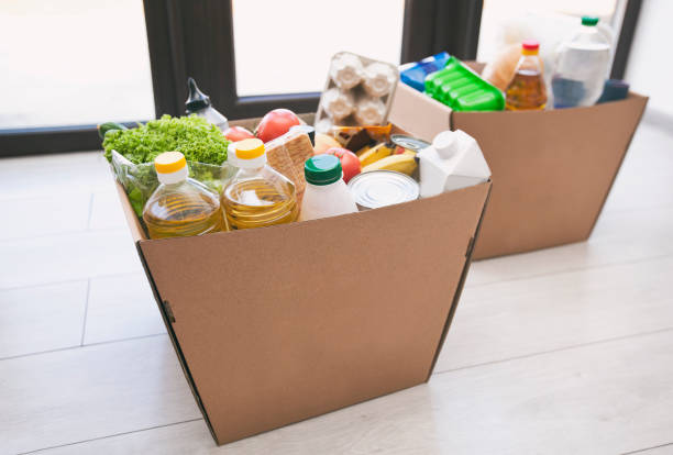The full cardboard eco box with products from the grocery store on the floor at home near the door stock photo