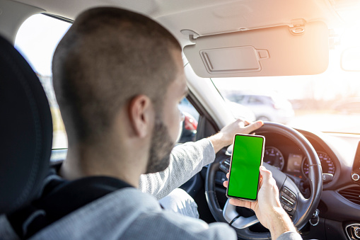 Man using a phone while driving. Green screen. Dangerous driving.