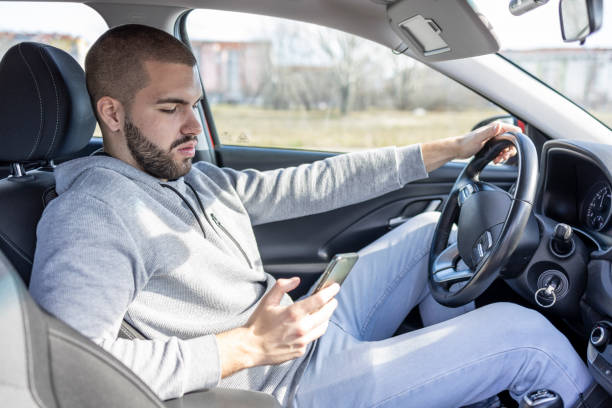 istock A man looks at his phone while driving 1469915696