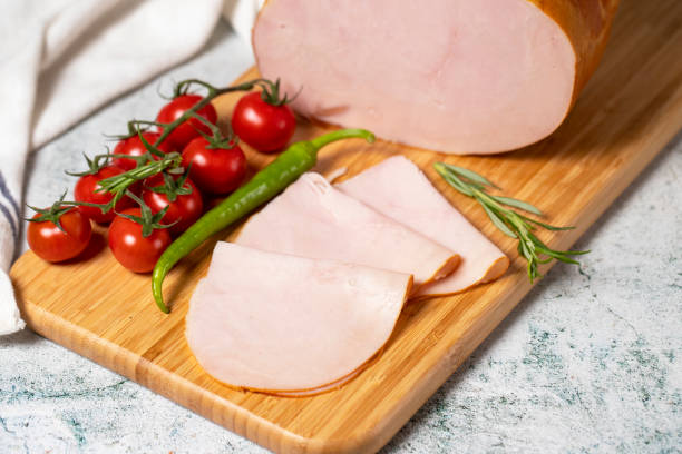 Smoked turkey meat sliced. Smoked turkey/ham fillets on a wood serving board. Deli products. Close up stock photo