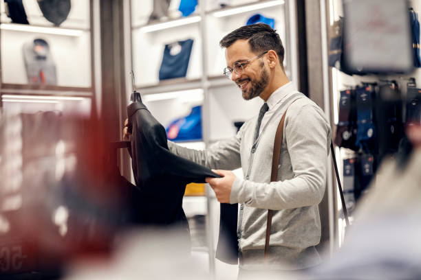 istock A happy elegant man is standing at store, holding and looking at suit. 1469917905