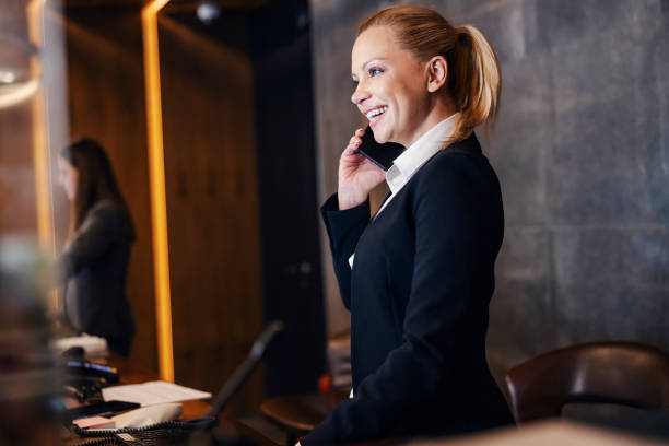 A happy receptionist is making reservation at hotel reception. stock photo