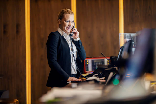 istock A happy receptionist is talking with guest on the phone and making the reservation while standing in hotel at reception. 1469919285