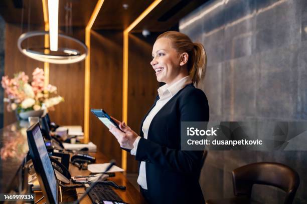 A Happy Receptionist Is Talking With Hotel Guest And Making A Reservation On A Tablet Stock Photo - Download Image Now