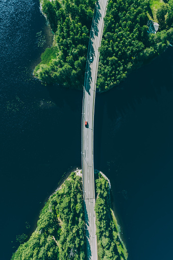 Aerial view of bridge road through blue lakes with green woods in summer Finland.