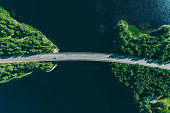 Aerial view of bridge road through blue lakes with green woods in Finland.