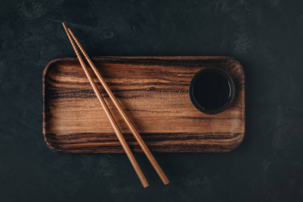 istock Empty wooden sushi plate with chopsticks on dark black stone background 1469921403