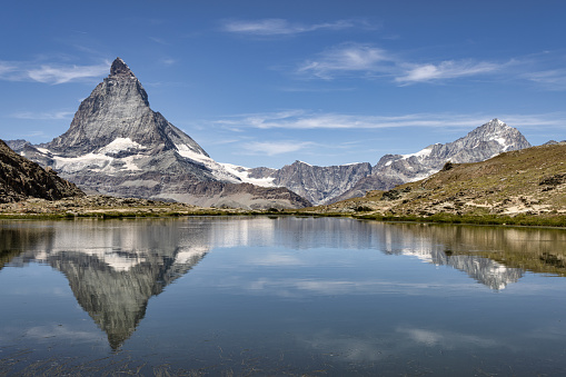 Swiss Alps Matterhorn Mountain Peak in Summer reflecting in Riffelsee Lake under blue sunny summer Skyscape. Riffelsee , Matterhorn, Zermatt, Switzerland, Europe.