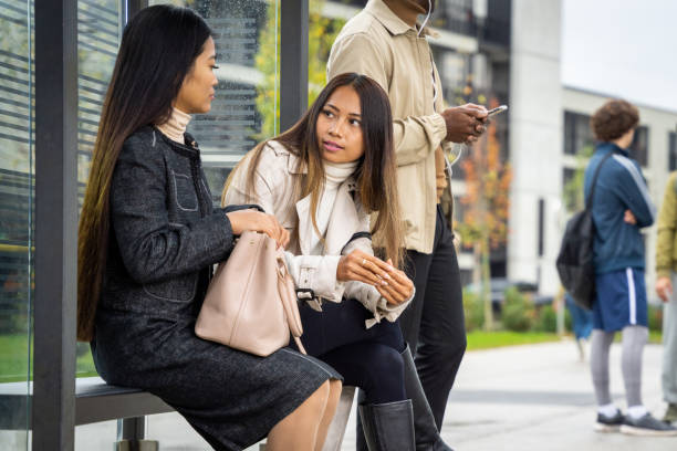 istock Attractive hispanic women chatting while sitting at bus stop 1469929246