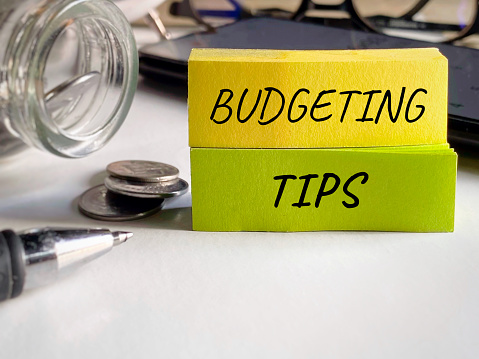 Budgeting tips text written on notepaper background. Financial concept.