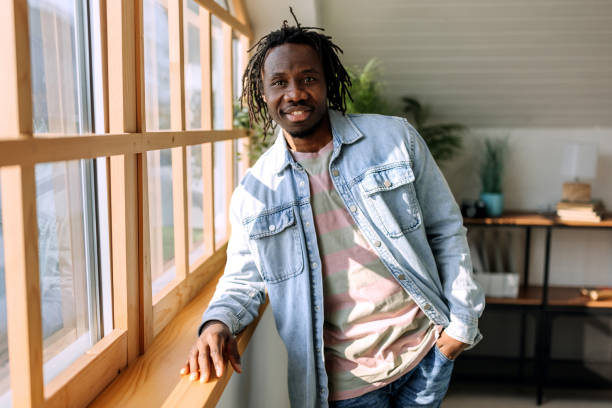 istock Young casually clothed man posing for a shot while standing near the window with a wooden frame 1469938136