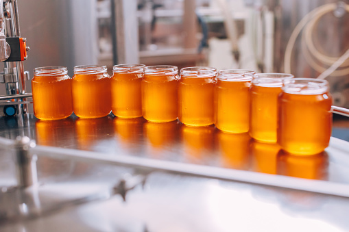 jars filled with golden honey freshly prepared in the production chain