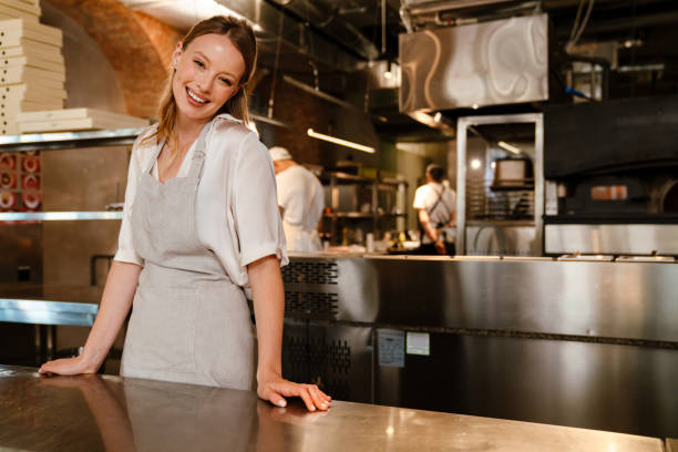 istock Young woman standing by counter while working in restaurant kitchen 1469939716