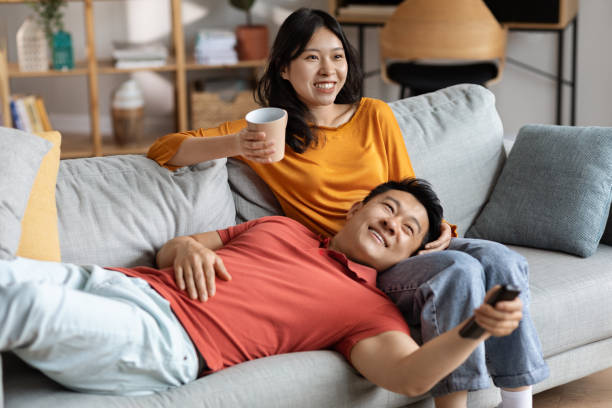 istock Relaxed chinese lovers resting together at home, watching TV 1469940708