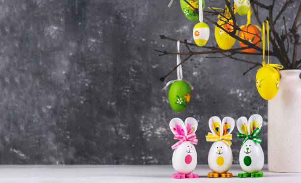 istock Vase with branches decorated with Easter eggs. Funny bunnies made of eggshells.Easter decoration, space for a text. 1469942348