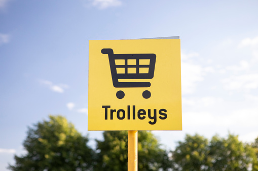 Yellow shopping trolley sign in a supermarket car park in summer