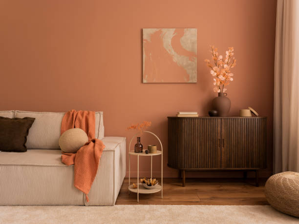 istock Creative composition of living room interior with mock up poster frame, wooden sideboard, modular beige sofa, brown pouf, plaid, pillows, rug, pink wall and personal accessories. Home decor. Template. 1469948582
