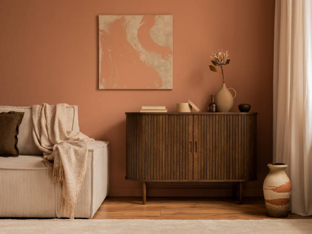 istock Creative composition of living room interior with mock up poster frame, wooden sideboard, modular beige sofa, brown pouf, plaid, pillows, rug, pink wall and personal accessories. Home decor. Template. 1469948645