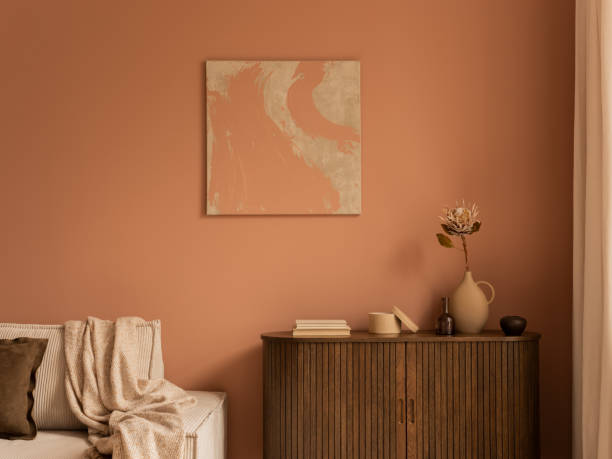 istock Creative composition of living room interior with mock up poster frame, wooden sideboard, modular beige sofa, beige plaid, pillows, pink wall and personal accessories. Home decor. Template. 1469948715