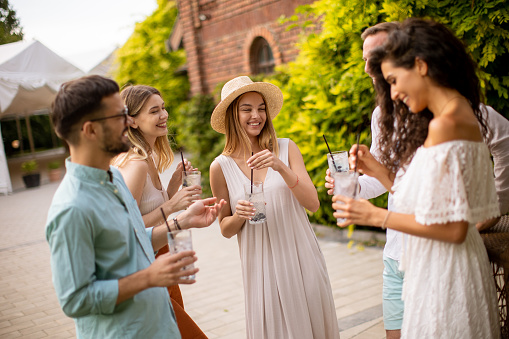 Group of young people gather outdoors to enjoy each other's company and refreshing glasses of lemonade
