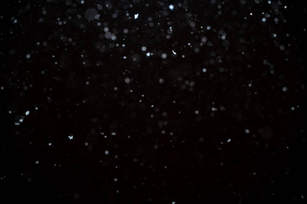 黒い背景に降雪。抽象的な白いボケ背景。