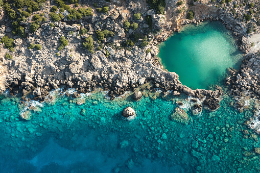 Small turquoise crater, surrounded by rocks, forming a small salt lake (Crete, Greece).