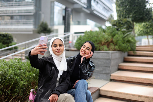 Arab women taking a selfie. Both about 25 years old, Middle Eastern female.