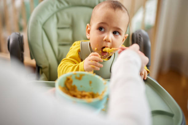 istock Mother spoon feeding her baby son at home 1469950557