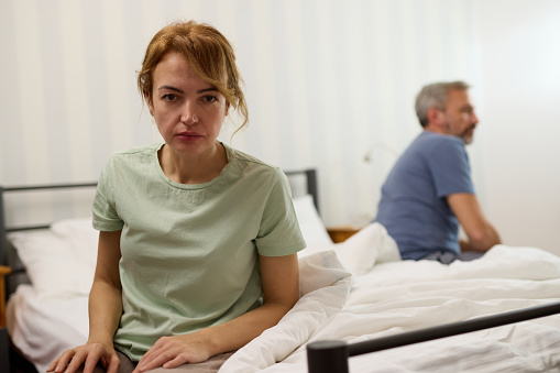 Couple sitting on different sides of bed not talking after argument