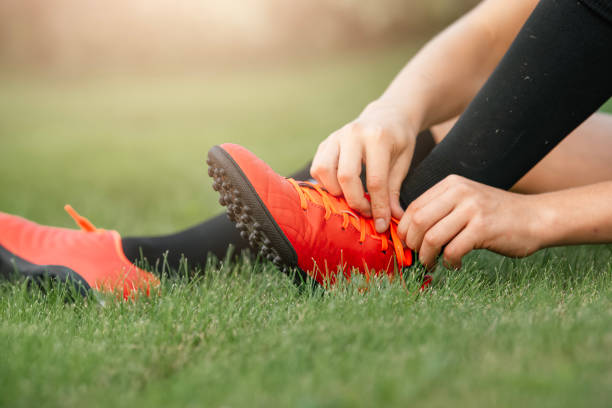 Football player tying shoelaces. The concept of preparation and safety of the game of football. Children's football club. Close-up of a football boot. child tied up stock pictures, royalty-free photos & images