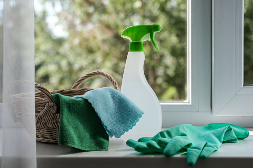 Cleaning agent, wipes and rubber gloves in a basket on the windowsill. General cleaning concept