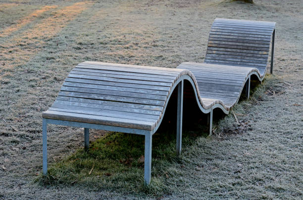 design bench in the shape of a wavy line. wooden paneling on a metal galvanized frame. The bench is atypical to order in a city park for young people and unusual sitting and lying, icing, winter, cold design bench in the shape of a wavy line. wooden paneling on a metal galvanized frame. The bench is atypical to order in a city park for young people and unusual sitting and lying, icing, winter, cold jump board stock pictures, royalty-free photos & images