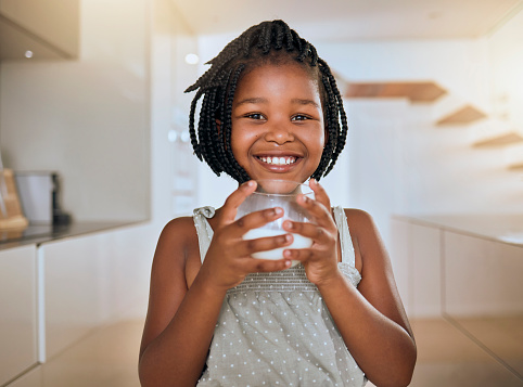 Child, happy and healthy milk drink for energy vitamins or health wellness at home. Black girl portrait, glass and breakfast nutrition or young kids teeth health care lifestyle in family home
