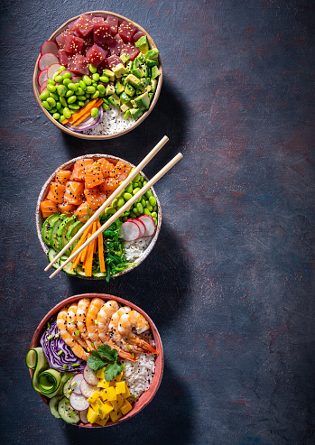 Poke bowls varied, salmon Poke, Tuna Poke and Shrimp Poke assorted on gray dark background