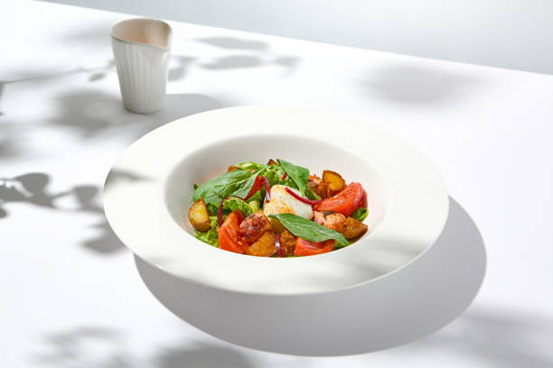 istock Salad with octopus, baked potatoes and poached egg on white table with hard shadows. Seafood salad with vegetables and potatoes in summer menu restaurant. Octopus and eggs salad in modern style. 1469958334