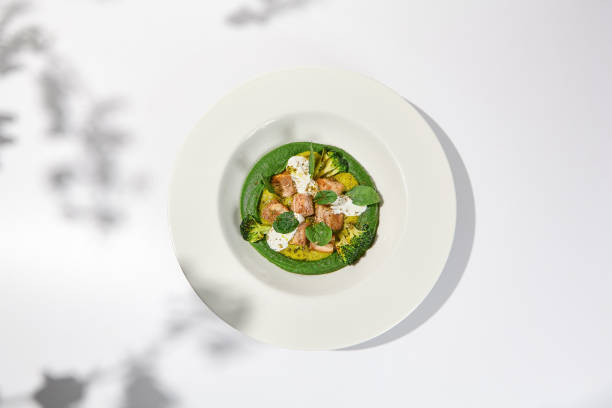 istock Creative dish from roasted chicken and broccoli puree on white plate. Sliced baked chicken with vegetables and creamy espuma in summer menu. 1469958376