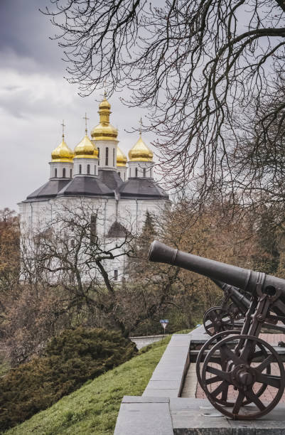 starożytne ciężkie stalowe armaty na tle cerkwi w parku miejskim miasta czernihów, przy pochmurnej wiosennej pogodzie - czernichów zdjęcia i obrazy z banku zdjęć