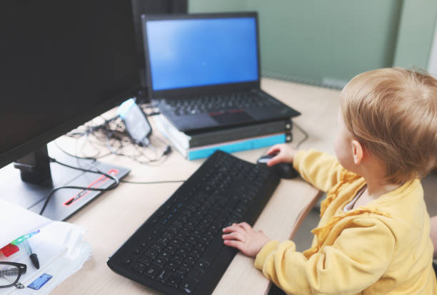 istock Cute 2 year old girl busily working at a home computer 1469958898