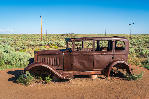 An old broken vintage car thrown in a desert