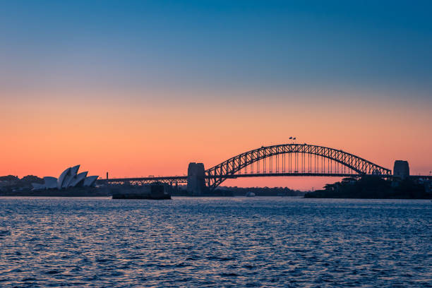 Sydney Harbor Bridge and Opera House during Sunset seen from the Sea, New South Wales, Australia Sydney Harbor Bridge and Opera House during Sunset seen from the Sea, New South Wales, Australia. sydney sunset stock pictures, royalty-free photos & images