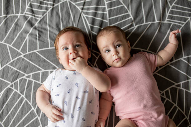 Cute twin boy and girl babies portrait lying on bed