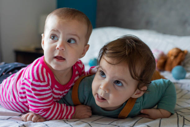Cute twin boy and girl babies portrait lying on bed